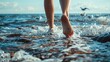 © fivan - Bare feet walking along a rocky shore, with waves crashing nearby and seagulls in the distance
