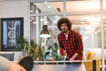 Wall Mural -  Business colleagues take a break from work to enjoy a game of table tennis, fostering teamwork and camaraderie in the workplace