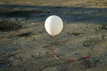 Poster - A small white balloon is tied to a bright red string, ready for flight