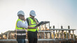 © SAHARAT - Two Architect man discussing about the building plan and see how the construction progressive at the construction site