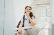 © Dusan - One young caucasian woman student sitting on stairs near university listening to music and drinking coffee