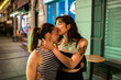 © Marko Geber - Lesbian couple kissing on city street at night