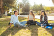 © Manu Padilla/Stocksy - Friends sitting on campus grass