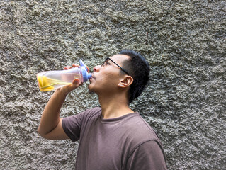 A man Southeast Asia drinking infused water lemon and grass lemon, in bottle, on the outdoor, fresh drink, healthcare, stock photo.