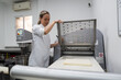 © Raul Navarro/Stocksy - Female baker preparing dough with industrial roller machine