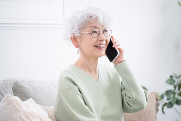 Wall Mural - close-up of smiling elderly (senior) woman in profile holding and talking on her cell phone (cell ph