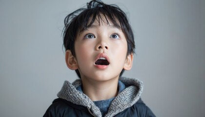 wonderstruck asian child with eyes wide open in awe on plain background