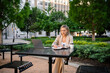 © DZ FILM/Stocksy - A woman uses a laptop sitting outdoors