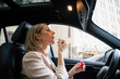 © DZ FILM/Stocksy - A woman paints her lips in a car