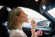 © DZ FILM/Stocksy - A woman paints her lips in a car