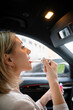 © DZ FILM/Stocksy - A woman paints her lips in a car