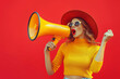 © btiger - Excited Fashion Woman with Loudspeaker on Red Background Announcing Final Sales Discounts Black Friday Stylish Brunette in Yellow Outfit with Hat and Sunglasses Screaming for Shopping Deals
