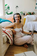 © BONNINSTUDIO/Stocksy - Smiling woman enjoying music while working on laptop at home