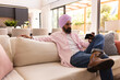 © Wavebreak Media - Relaxing on couch, man in turban using smartphone in modern living room, copy space