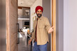 © Wavebreak Media - Welcoming guests, man in turban opening door and inviting inside home