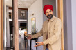 © Wavebreak Media - Welcoming guests, man in red turban inviting into modern home interior