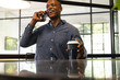 © Wavebreak Media - Talking on smartphone, man holding coffee cup and smiling in modern office