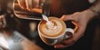 © kwanchaift - A barista creating latte art in a cup of coffee, showcasing the skill and creativity involved in making the perfect cup