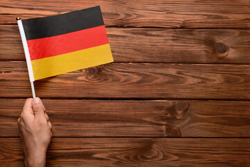 Wall Mural - Male hand with flag of Germany on wooden background