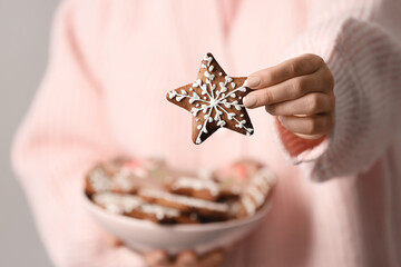 Sticker - Woman holding Christmas gingerbread cookie on grey background, closeup view