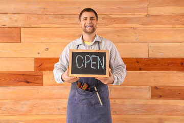 Wall Mural - Male shoemaker with OPEN sign on wooden background