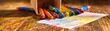 © Tin - Colorful crayons scattered on a wooden table with a vibrant drawing paper, bright crayons, art supplies, close-up view.