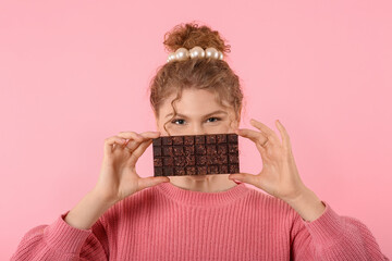 Wall Mural - Beautiful young woman with sweet chocolate bar on pink background