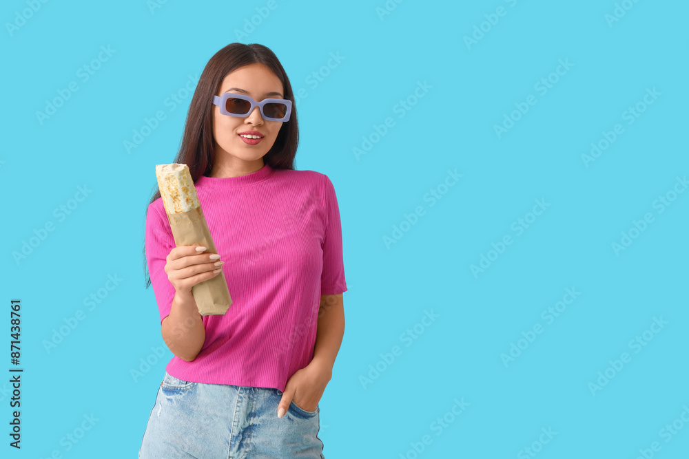 Young Asian woman with doner kebab on blue background