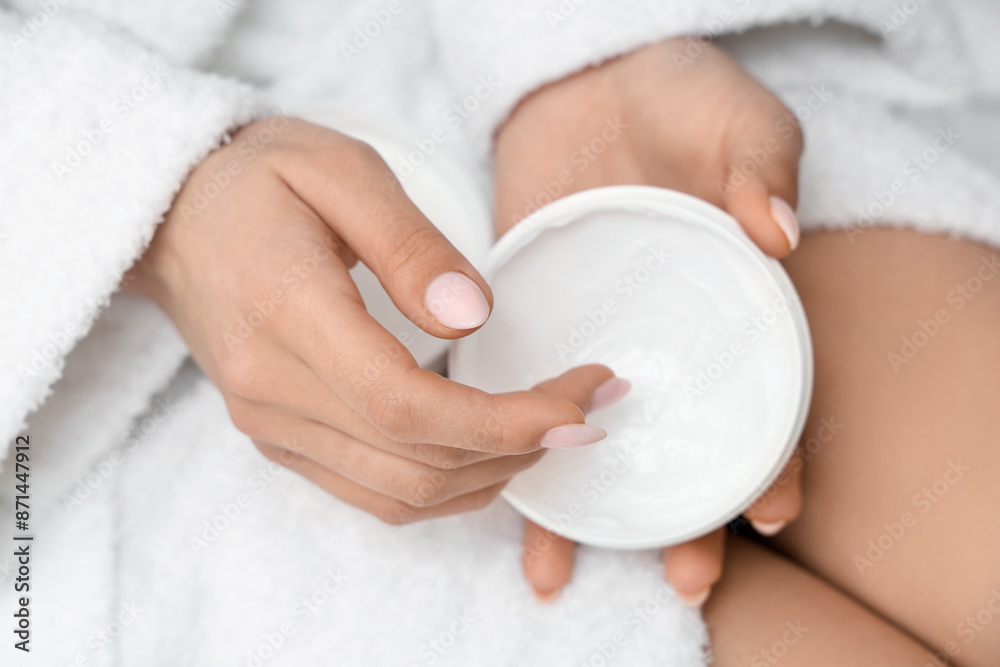Woman in bathrobe applying natural cream on her hand, closeup