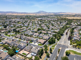 Wall Mural - Drone photo over a suburban neighborhood in Brentwood, California with homes, streets and a blue sky