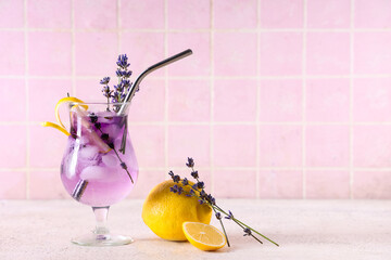 Glass of fresh lavender lemonade with flowers and lemon on white table