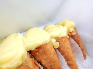 Closeup view of four delicious Greek cream-filled phyllo cones (trigona panoramatos), a traditional dessert from Thessaloniki, Greece.