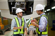 © offsuperphoto - Engineers or technicians checking railroad and talking with coworkers at train station construction site