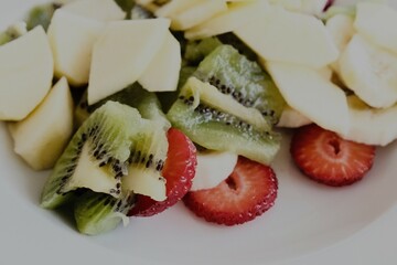 white plate with fresh seasonal fruit. a fruit salad for a typical healthy and nutritious Italian breakfast