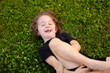 © Vasil - a little girl is lying on the grass playing with her mother. Cheerful and happy child