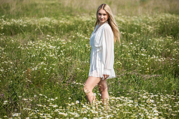 Wall Mural - Portrait of a young beautiful blonde in a chamomile field