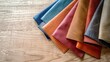 © pngking - Various colored leather samples displayed on light wood surface