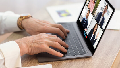 Poster - A person is typing on a laptop during a video conference meeting with four other people. The laptop screen shows four video boxes with different people, each in their own workspace.
