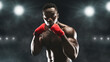 © Prostock-studio - A boxer in red hand wraps stands ready in a dark stadium, illuminated by bright lights.