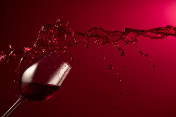 Poster - Glass and red wine splash on a dark red background.