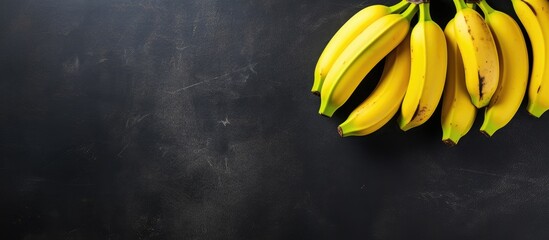 Poster - Aerial perspective showing four bananas on a dark slate surface with copy space image to the right.