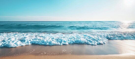 Poster - Ocean waves gently lapping the sandy shore create a calming scene with a breathtaking view of the horizon and a clear blue sky in the background with copy space image.