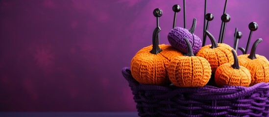 Poster - Composition with knitted orange pumpkins in a basket, a crochet hook, on a purple background with copy space image. Autumn-themed, perfect for a Halloween concept.