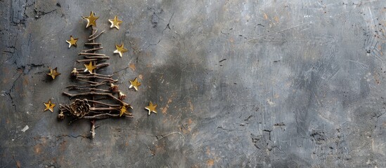 Poster - Flat lay silhouette of a Christmas tree crafted from wooden twigs adorned with gold star sequins on a gray concrete background with copy space image.