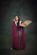 © master1305 - Humorous ads for pizza brands. Portrait of young woman, royal person in rich dress, eating pizza against vintage green background. Concept of history, comparison of eras, remake, restaurant
