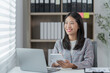 © Tj - Sharing good business news. Attractive young businesswoman talking on the mobile phone and smiling while sitting at her working place in office and looking at laptop PC.