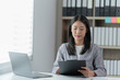 © Tj - Sharing good business news. Attractive young businesswoman talking on the mobile phone and smiling while sitting at her working place in office and looking at laptop PC.