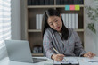 © Tj - Sharing good business news. Attractive young businesswoman talking on the mobile phone and smiling while sitting at her working place in office and looking at laptop PC.