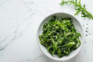 Canvas Print - Delicious seaweed salad in a bowl on a white marble table top view Room for text