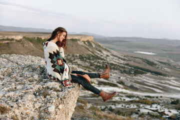 Wall Mural - Solitude in the mountains a woman peacefully sits on a rock surrounded by majestic peaks in the distance